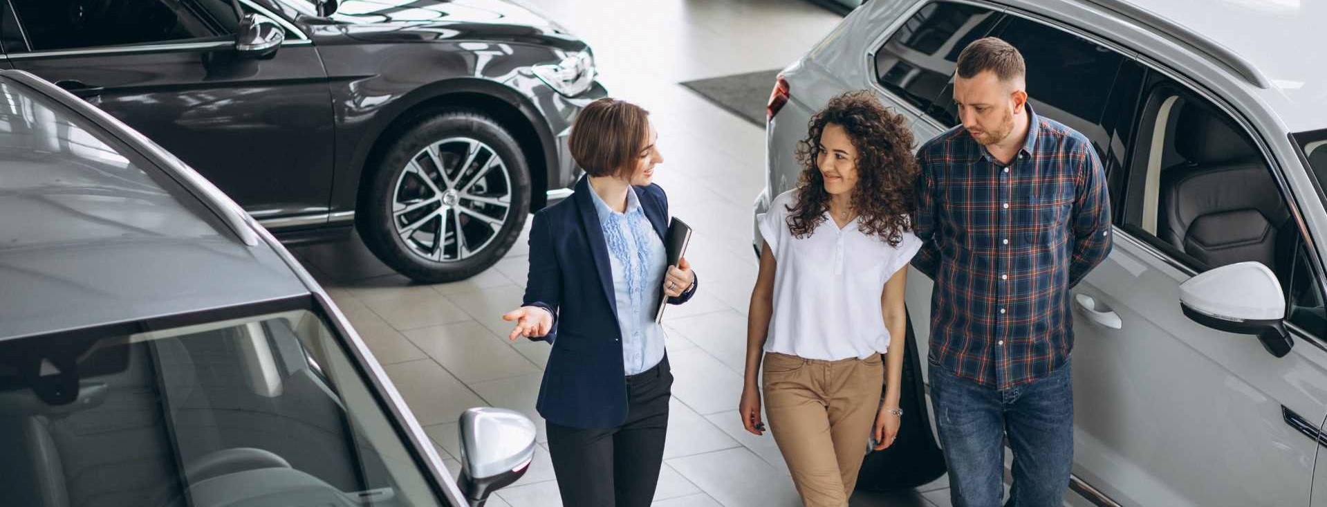 /yoyoautocentreltd/1622582637367178-13439563052774384-young-couple-talking-sales-person-car-showroom.jpg